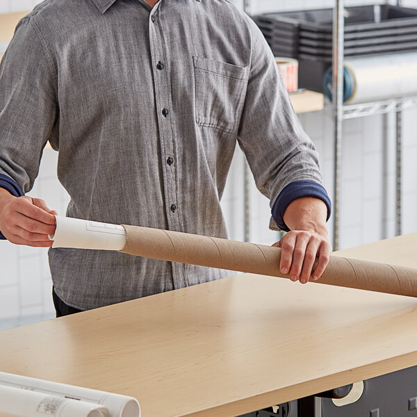 A man holding a Lavex Kraft cardboard mailing tube.