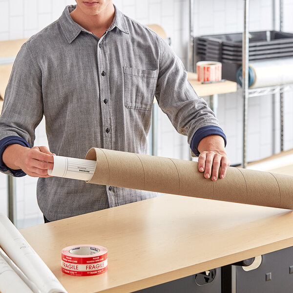 A man holding a Lavex Kraft Snap Seal Mailing Tube filled with paper.