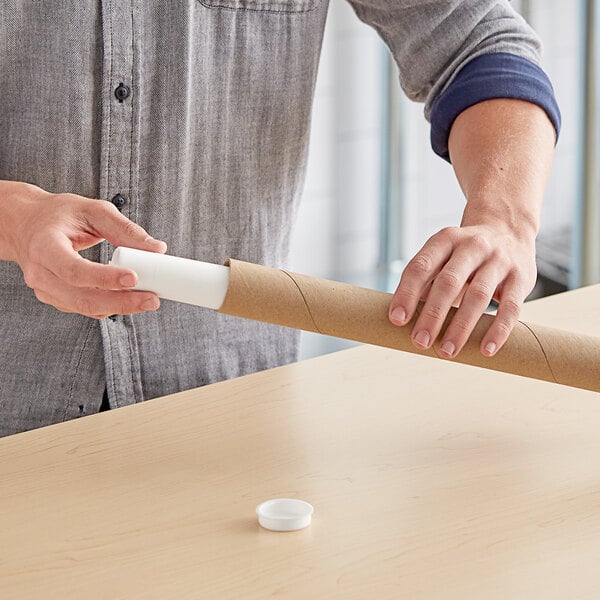 A person holding a Lavex Kraft mailing tube of paper.