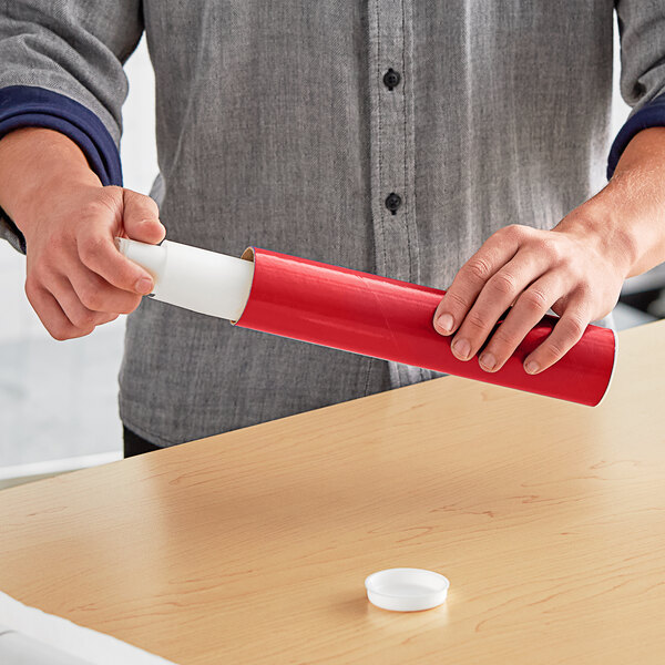 A person holding a red Lavex mailing tube over a table.