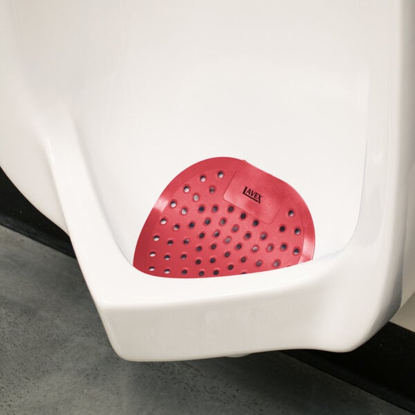 A urinal with a red urinal screen with a red circle in the center.