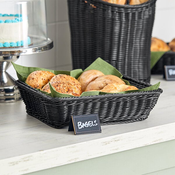 A black woven plastic rattan basket filled with bread on a bakery table.