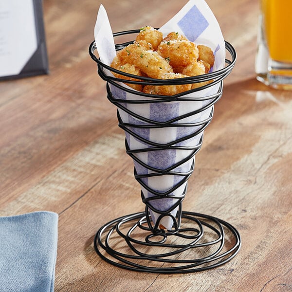 An American Metalcraft black wire birdnest basket filled with food on a table.