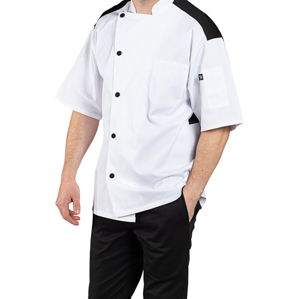 A man wearing a Uncommon Chef white short sleeve chef coat with mesh back.