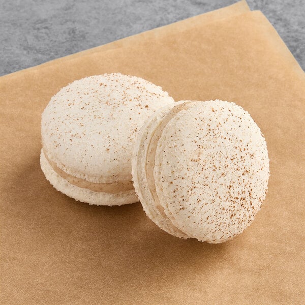 Two Macaron Centrale vegan snickerdoodle macarons on brown paper.