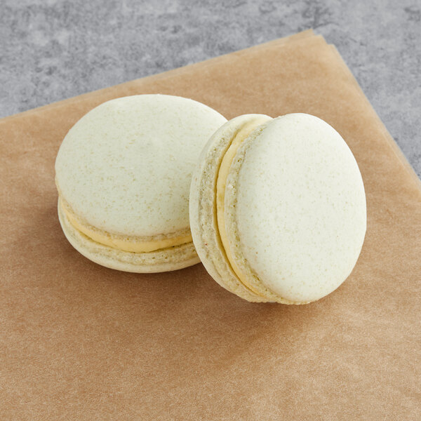 Two white Macaron Centrale macarons with yellow filling on a brown napkin.