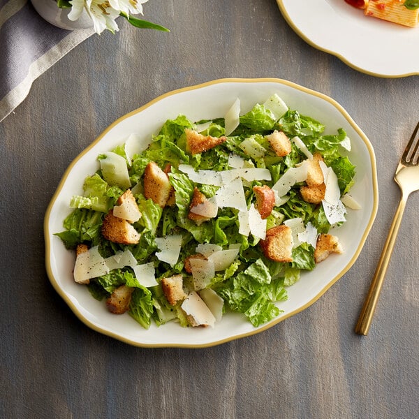 A CAC ivory china platter with a salad topped with croutons and parmesan cheese.