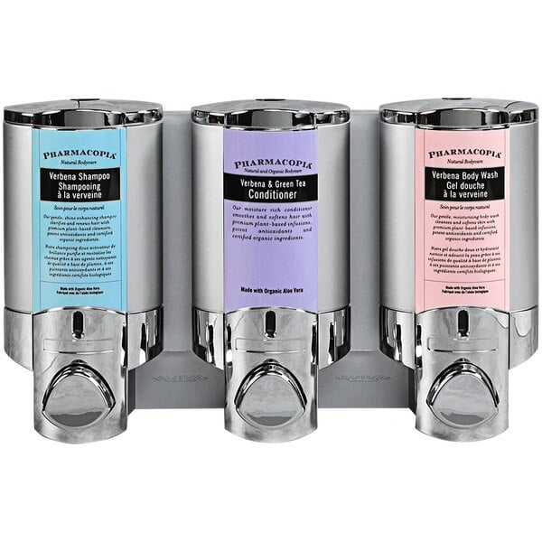 A wall mounted chrome Dispenser Amenities Aviva 3-chamber shower dispenser with satin silver bottles and a Pharmacopia logo.
