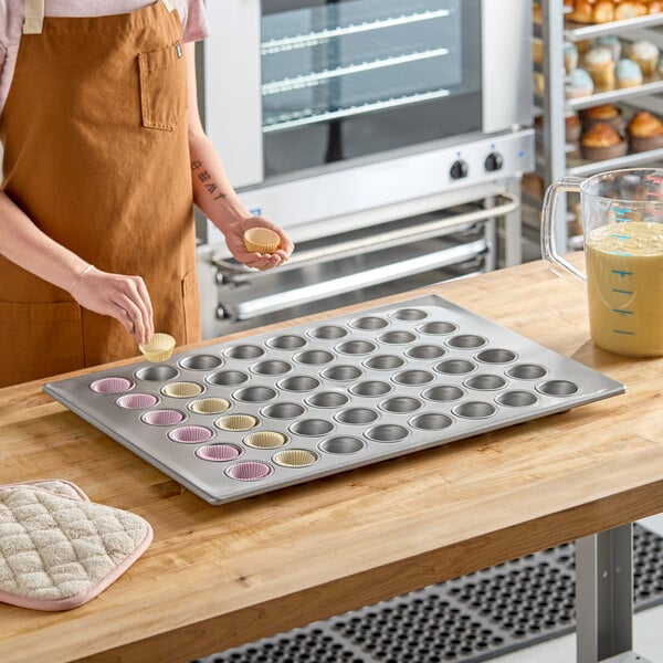 A large 48-cup glazed aluminized steel mini muffin or cupcake pan on a wooden countertop.