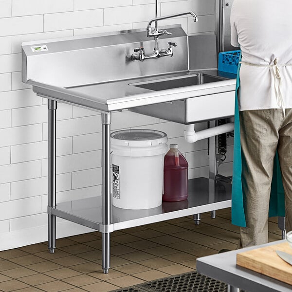 A man standing next to a Regency stainless steel dish table undershelf next to a sink.