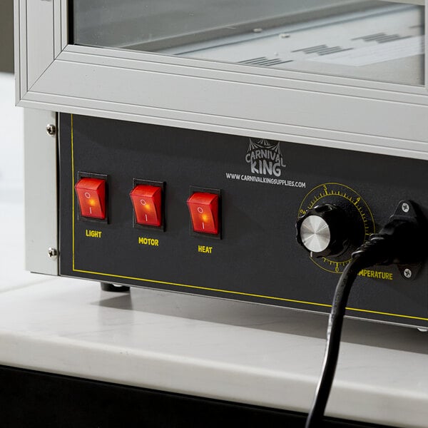 A close-up view of a control panel with three red switches labeled 'Light,' 'Motor,' and 'Heat,' a temperature dial, and part of a glass enclosure above.