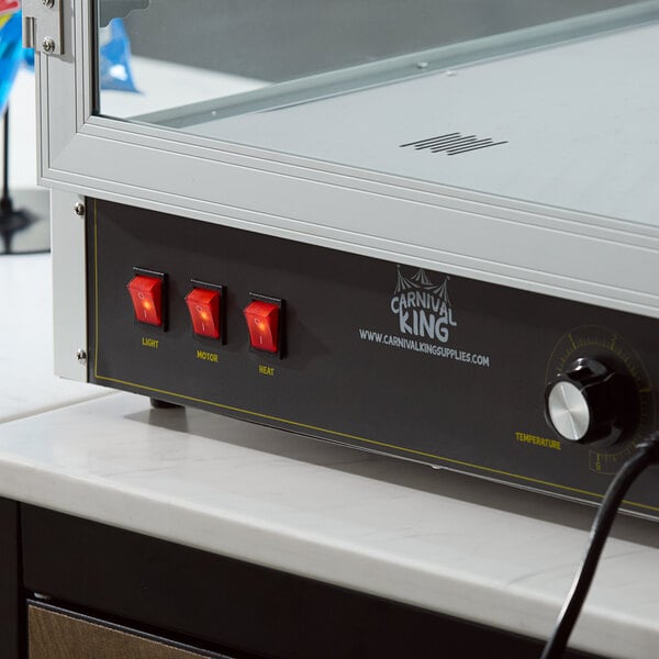 A partial view of a countertop display warmer with three red switches labeled 'Light,' 'Motor,' and 'Heat,' a temperature control knob, and a glass enclosure.