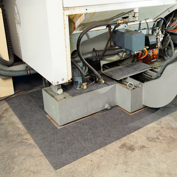 A heavy weight absorbent mat roll placed under industrial machinery to catch leaks and spills.