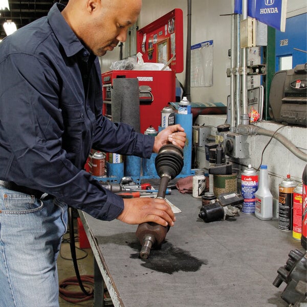 A person working in a garage with a New Pig MAT225 absorbent lightweight mat roll on the workbench.