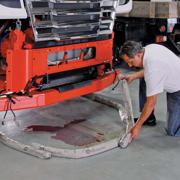A pack of New Pig 404 42-inch by 3-inch original absorbent socks being used to contain a liquid spill under a vehicle.