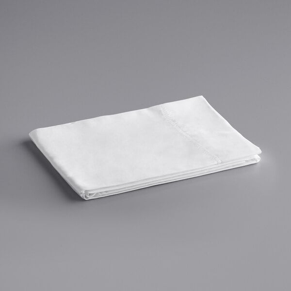 A folded white Oxford Super king size pillow case on a gray surface.