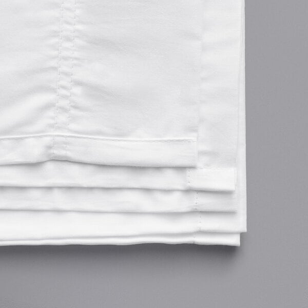 A stack of white Oxford Super full size flat sheets.