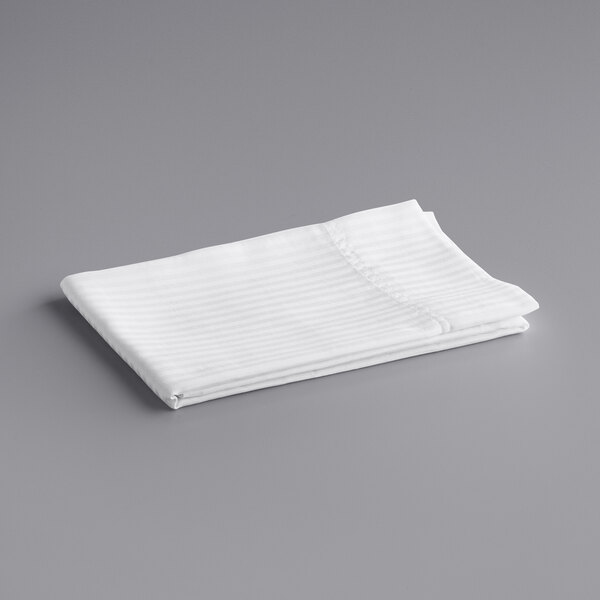 A folded white Oxford Super Blend pillow case with tone on tone stripes on a gray surface.