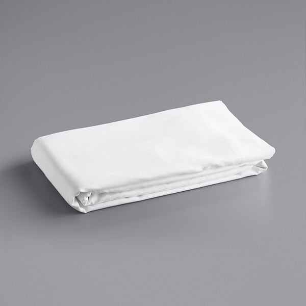 A folded white Oxford Super king size flat sheet on a gray surface.