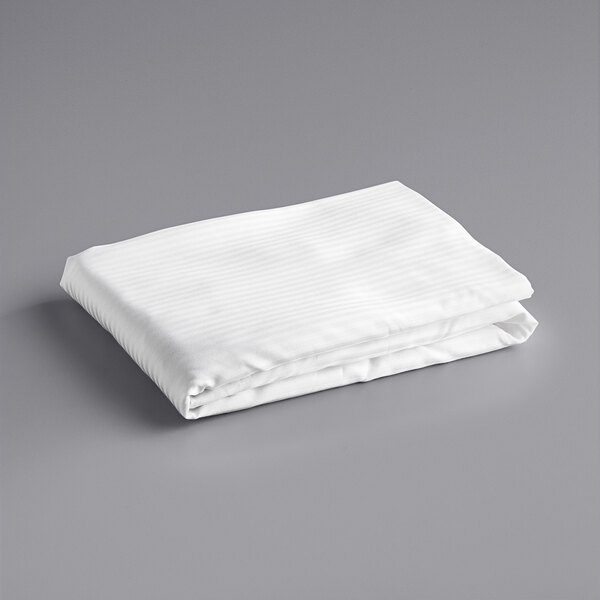 A folded white Oxford Superblend fitted sheet on a gray surface.