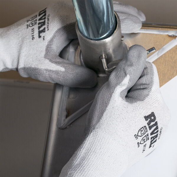 A person wearing Cordova Rival cut resistant gloves holding a metal pipe.