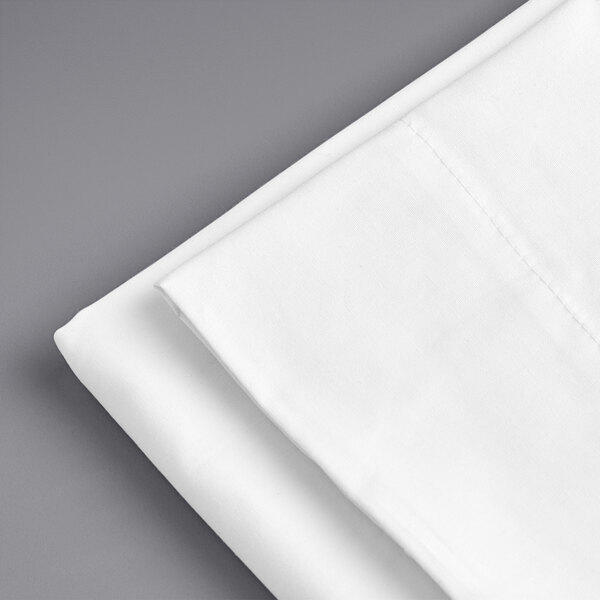 A folded white Welspun Hygrocotton pillow case on a gray surface.