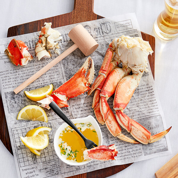 A Dungeness crab claw on a cutting board with a lemon slice.