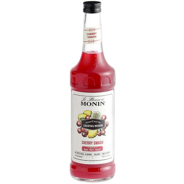 A bottle of Monin Cherry Smash cocktail mix with a red label and red liquid.