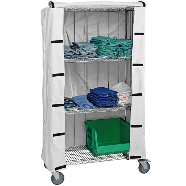 A Quantum white nylon cart cover on a white cart with shelves holding blue towels.