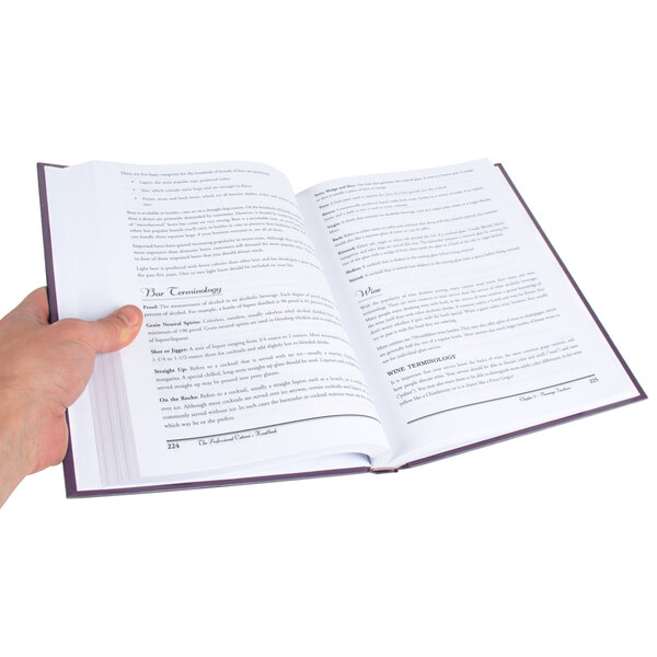 A hand holding an open book with text on it.