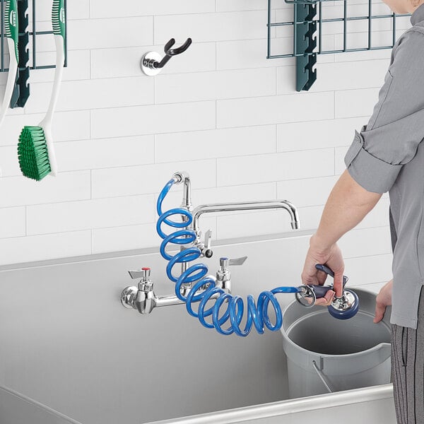 A woman using a Waterloo Pet Grooming angled spray valve to wash dishes in a sink.