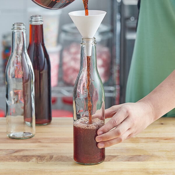 A person pouring red wine into a 375 mL burgundy wine bottle.