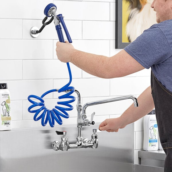 A man using a hose to open a Waterloo pet grooming faucet.