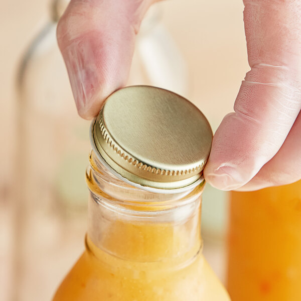 A person opening a jar with a gold metal lid.