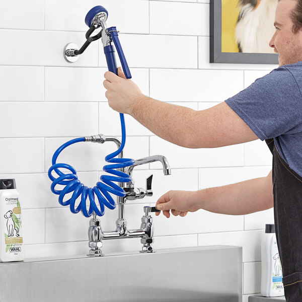 A man using a hose to open a Waterloo pet grooming faucet.