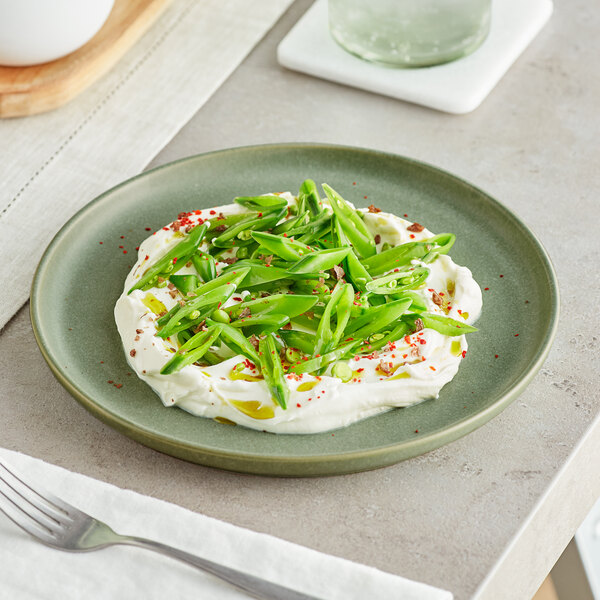 An Acopa Pangea sage matte coupe plate with green beans and cream cheese on it.