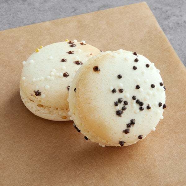 A white Macaron with white and black speckles on top and a brown Macaron.