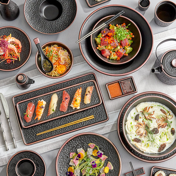 A table with Acopa Heika black stoneware bowls filled with food.
