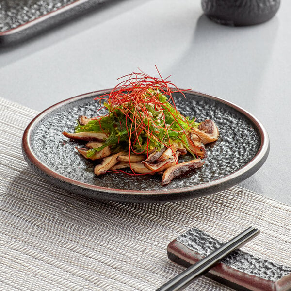 A black Acopa Heika stoneware plate with food on it.