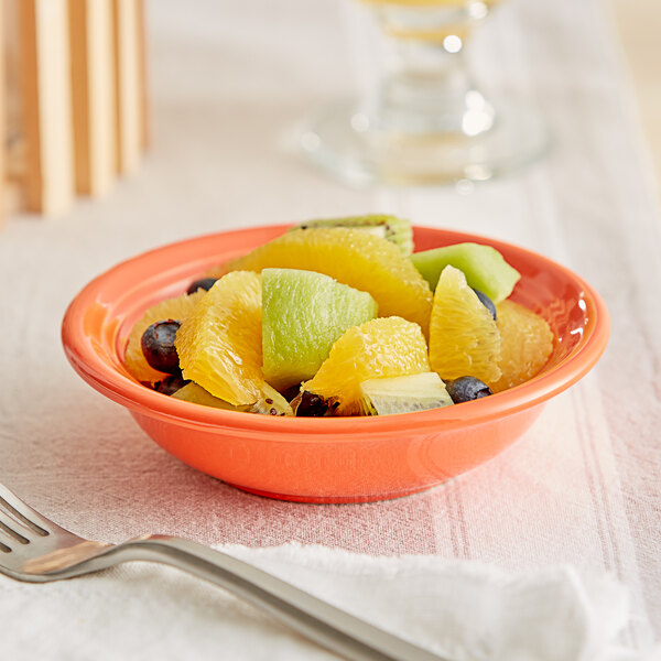 An Acopa Capri Valencia orange stoneware bowl filled with fruit on a table.