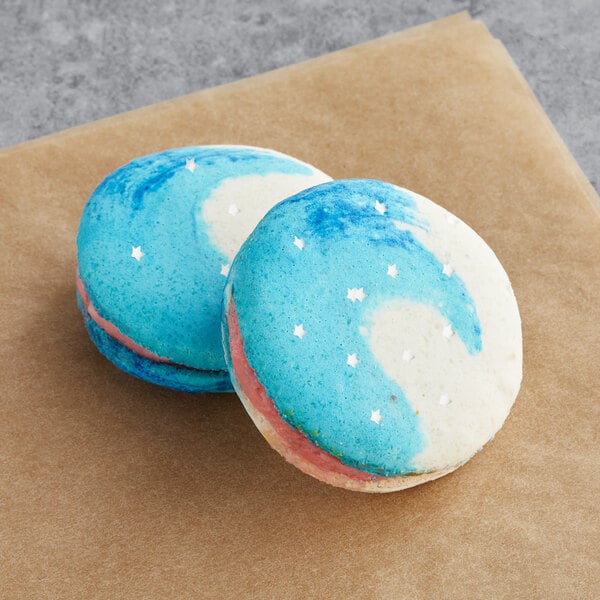 Two blue and white Macaron Centrale macarons on a brown surface.