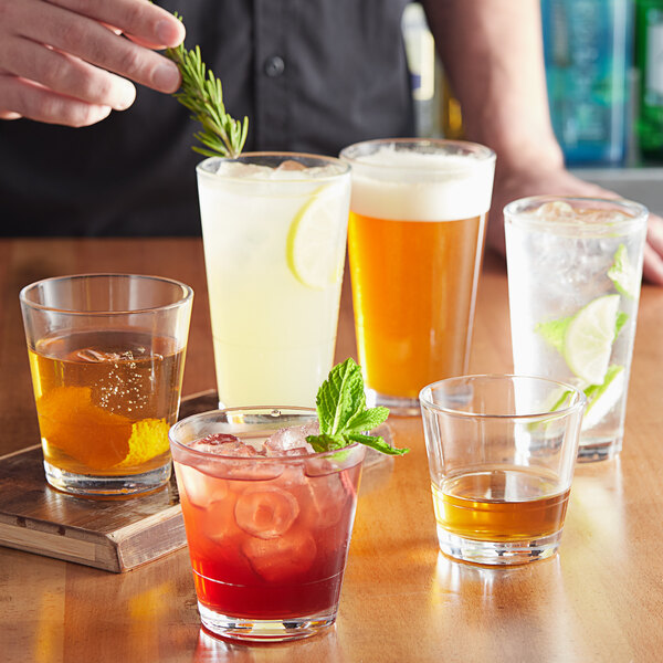 A bartender is pouring drinks into Acopa Select stackable glasses on a table in a cocktail bar.
