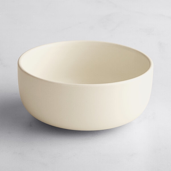 An Acopa Pangea fog white porcelain bowl on a white surface.