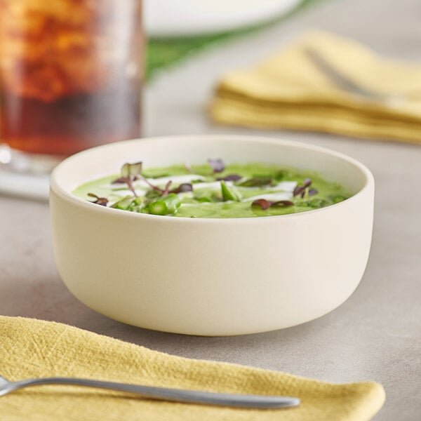 A bowl of soup on a table with a glass of water.