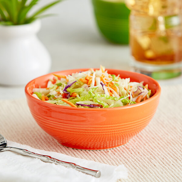 An Acopa Valencia orange stoneware bowl filled with coleslaw on a table.