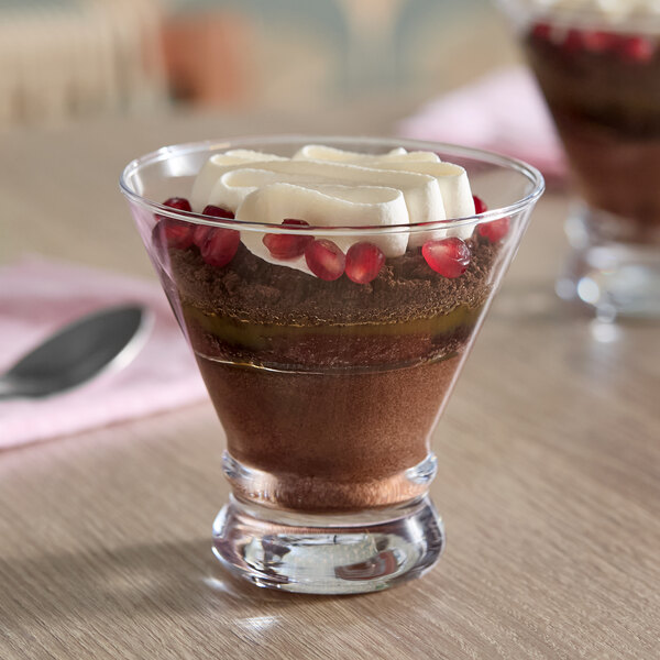 An 8 oz. stemless martini or dessert glass filled with a layered chocolate dessert, topped with whipped cream and pomegranate seeds.