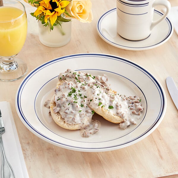 An Acopa stoneware plate with food, gravy, and a drink on it.