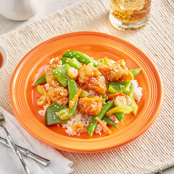 An Acopa Capri stoneware plate with Asian food on a table.