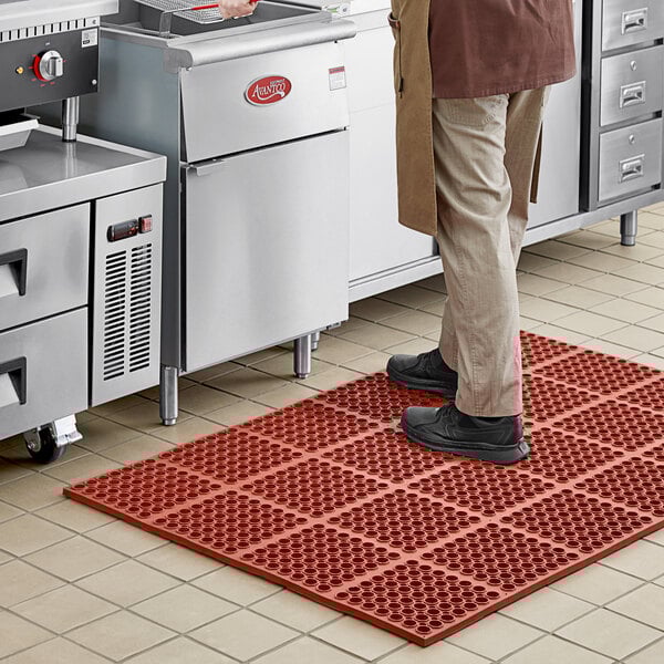 A person standing on a red Choice rubber anti-fatigue floor mat.