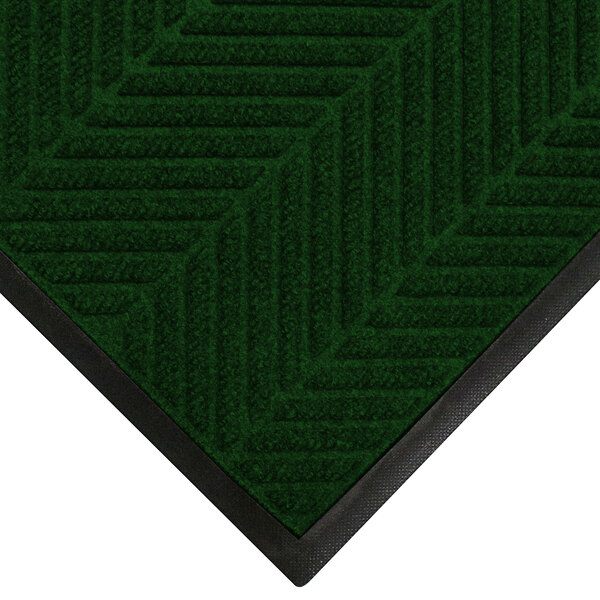 A green WaterHog mat with black trim and a pine tree pattern.